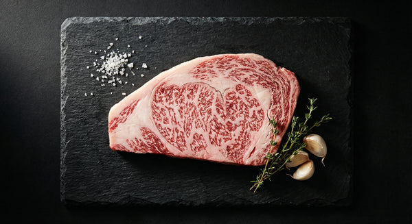 Premium Japanese A5 wagyu ribeye steak showing intense white marbling on black slate surface
