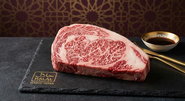 Premium halal-certified Japanese wagyu ribeye steak with intense marbling arranged on dark stone surface