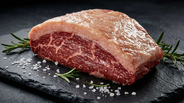 Raw picanha steak with thick fat cap on dark slate board - AI generated